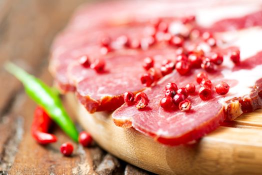 Cured meat with chilli pepper on cutting board