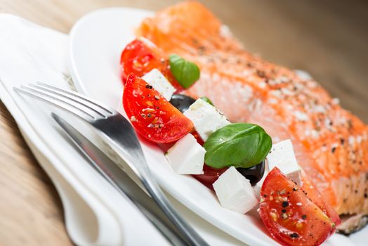 Grilled salmon on plate and greek salad