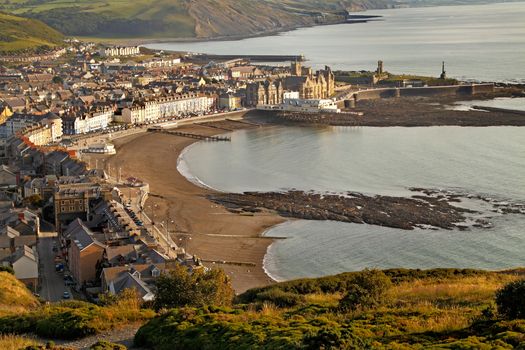 The evening sun lights up Aberystwyth in Wales, Uk, photographed from high above the town on Constitution Hill.