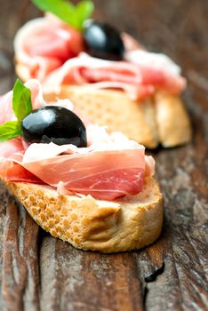 Sandwich with prosciutto, olive on wooden old table