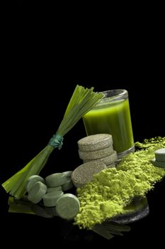 Chlorella, spirulina, wheat grass and young barley isolated on black background. Green superfood, healthy eating, alternative medicine and detox. 