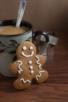 A gingerbread man cookie and a cup of fresh coffee on a wooden table.