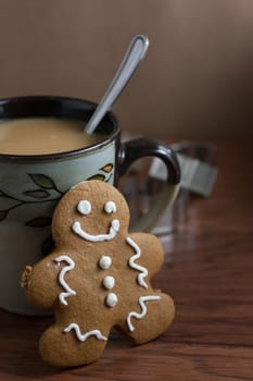 A gingerbread man cookie and a cup of fresh coffee on a wooden table.