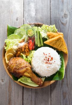Popular Indonesian local food nasi ayam penyet, indonesian fried chicken rice with sambal belacan. Fresh hot with steam smoke.