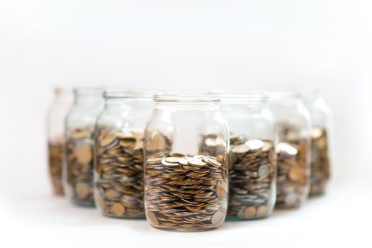 coins in a three glass jars against a white background