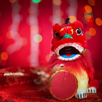 Chinese new year decorations, miniature dancing lion on red glitter background.