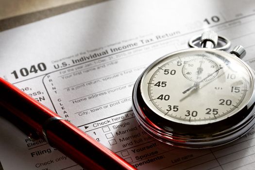 Tax form, red pen and stopwatch