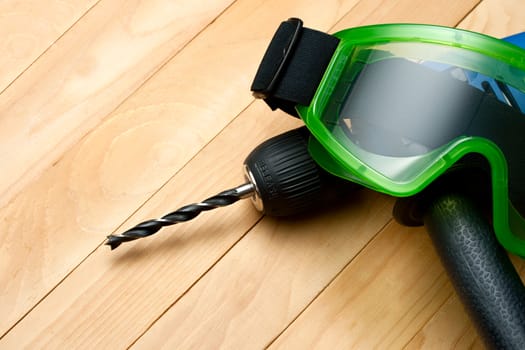 Handdrill and goggles on wooden background