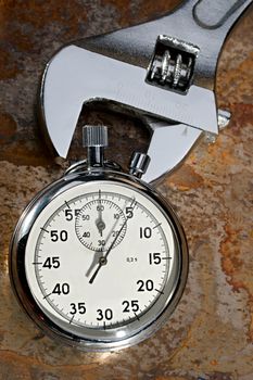 Spanner and stopwatch on the rusty plate