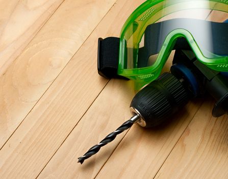 Handdrill and goggles on wooden background