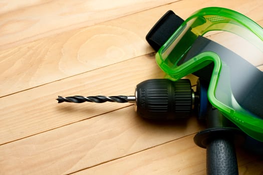 Handdrill and goggles on wooden background