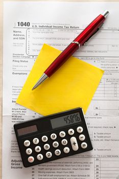 Tax form, red pen, calculator and sticker