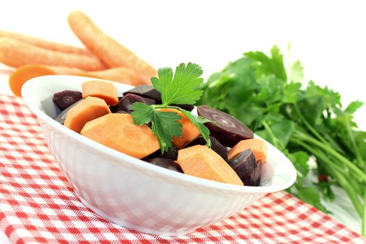 orange and purple carrots with parsley on a light background