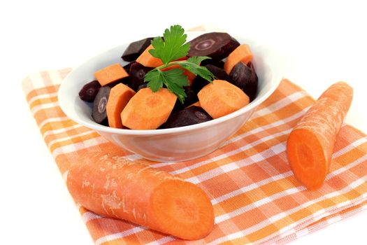orange and purple carrots with smooth parsley on a light background