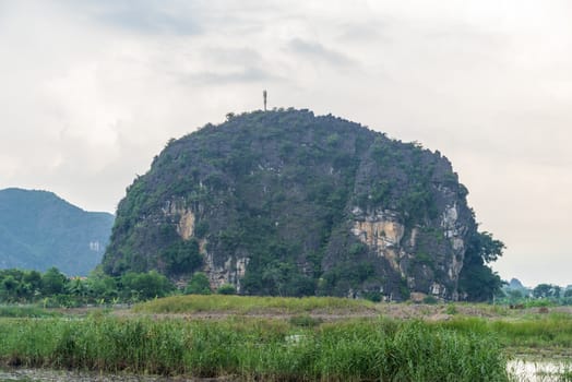 A steep small mountain in the middle of green field meadow