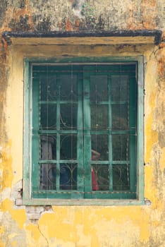 Green Windows with Steel bars On the old Yellow walls of the house