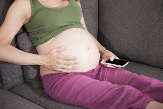 pregnant woman hand on tummy with smartphone