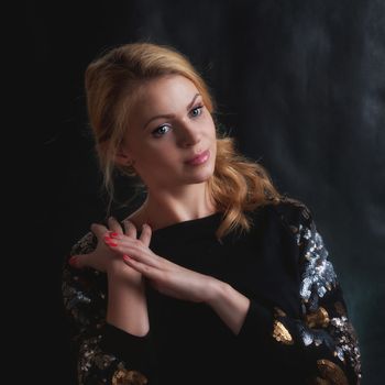 The blonde the girl in a dark blouse against a dark background