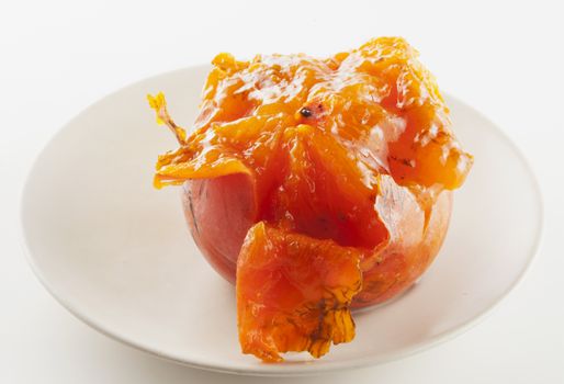 Open persimmon over plate, over white background
