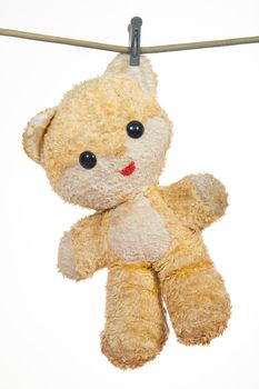 Old teddy bear hanging to dry on a string attach by clothes peg. Studio image. 