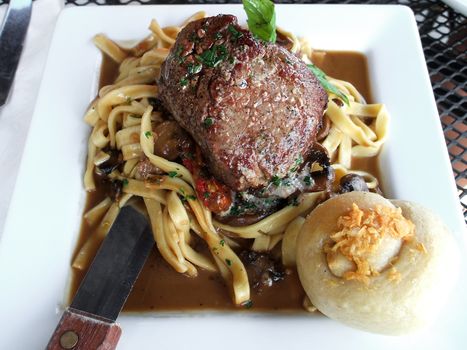 Petite filet mignon on a bed of homemage pasta with mushrooms and truffle oil.  Shallow depth of field. 