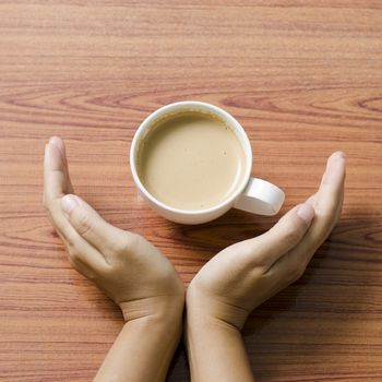 woman hand holding coffee cup on wood table background