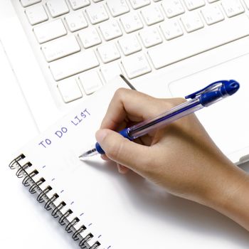 woman hand writing with pen on notebook write to do word and laptop over white background