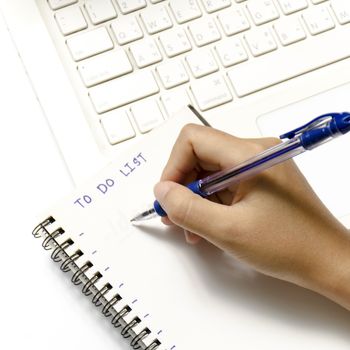 woman hand writing with pen on notebook write to do word and laptop over white background