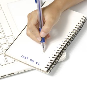 woman hand writing with pen on notebook write to do word and laptop over white background