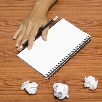 hand writing on notebook with crumpled paper on wood table background