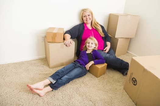 Happy Young Mother and Daughter In Empty Room With Moving Boxes.