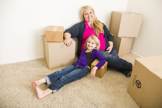 Happy Young Mother and Daughter In Empty Room With Moving Boxes.