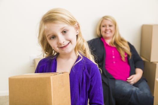 Happy Young Mother and Daughter In Empty Room With Moving Boxes.