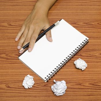 hand writing on notebook with crumpled paper on wood table background