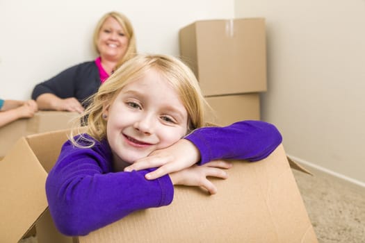 Happy Young Mother and Daughter Having Fun With Moving Boxes.