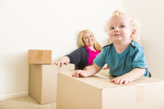 Playful Happy Mother and Son in Empty Room with Moving Boxes.