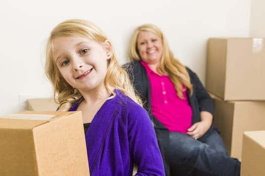 Happy Young Mother and Daughter In Empty Room With Moving Boxes.