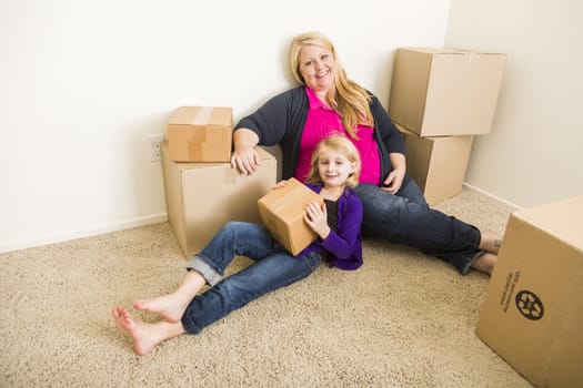 Happy Young Mother and Daughter In Empty Room With Moving Boxes.