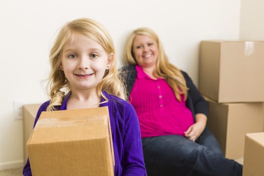 Happy Young Mother and Daughter In Empty Room With Moving Boxes.