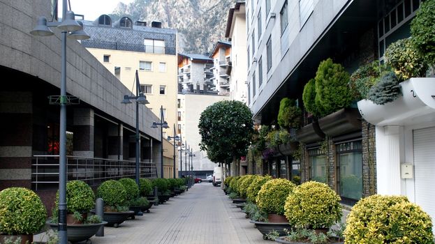 Clear street in Andorra-la-Vella with buildings and bushes.