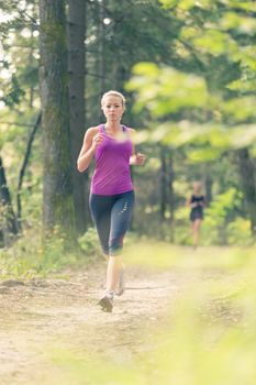 Pretty young girl runner in the forest.  Running woman. Female Runner Jogging during Outdoor Workout in a Nature. Beautiful fit Girl. Fitness model outdoors. Weight Loss. Healthy lifestyle. 