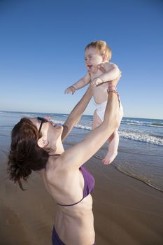 mother with baby up in her arms at beach