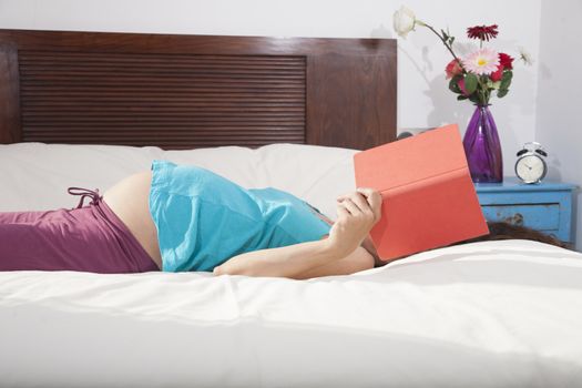 pregnant woman reading a book lying in bed