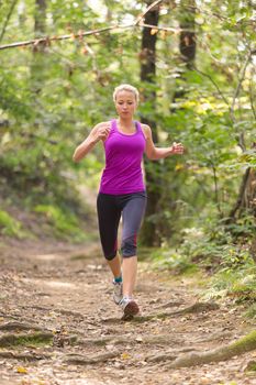 Pretty young girl runner in the forest.  Running woman. Female Runner Jogging during Outdoor Workout in a Nature. Beautiful fit Girl. Fitness model outdoors. Weight Loss. Healthy lifestyle. 