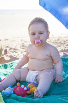 baby with white diaper on green towel at beach