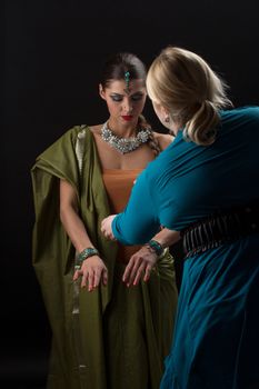 Make-up artist corrects make-up and clothes for the actress on black background