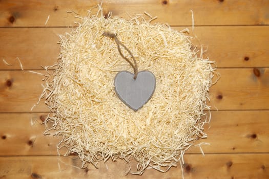 single grey wooden love heart in a love nest made of straw inscribed love is a sweet thing on floor boards