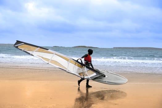 lone windsurfer getting ready to surf on the beach in the maharees county kerry ireland