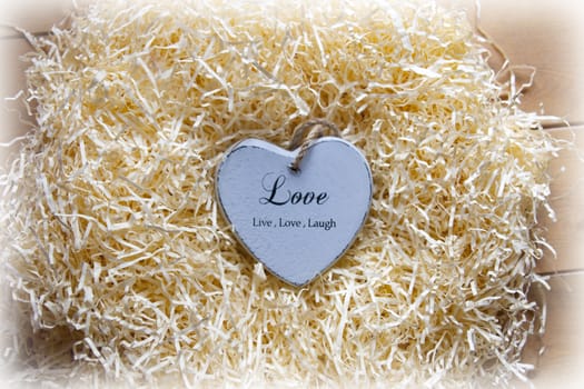 single blue wooden love heart in a love nest made of straw