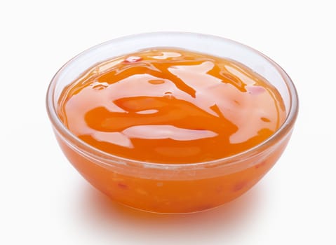 Orange sauce in the transparent sauce-boat on the white